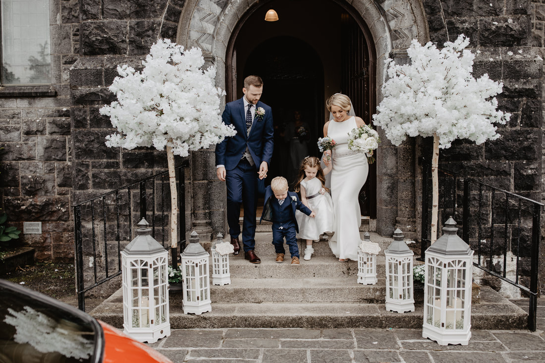 Wedding decor at a church, bride and groom exit. with their kids. Lovely white sakura trees. Best wedding photographer in Galway