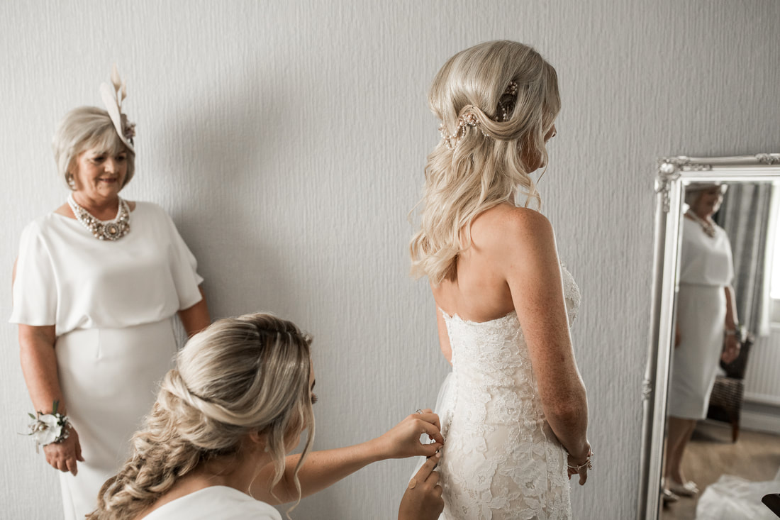 bridesmade helps to get into wedding dress
