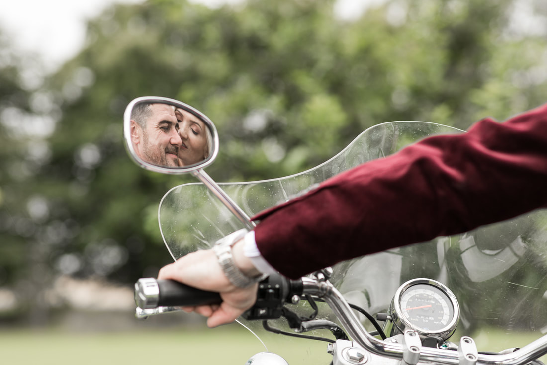 Bride and groom kissing, reflection on a bikes mirror. Creative wedding photographer in Dundalk