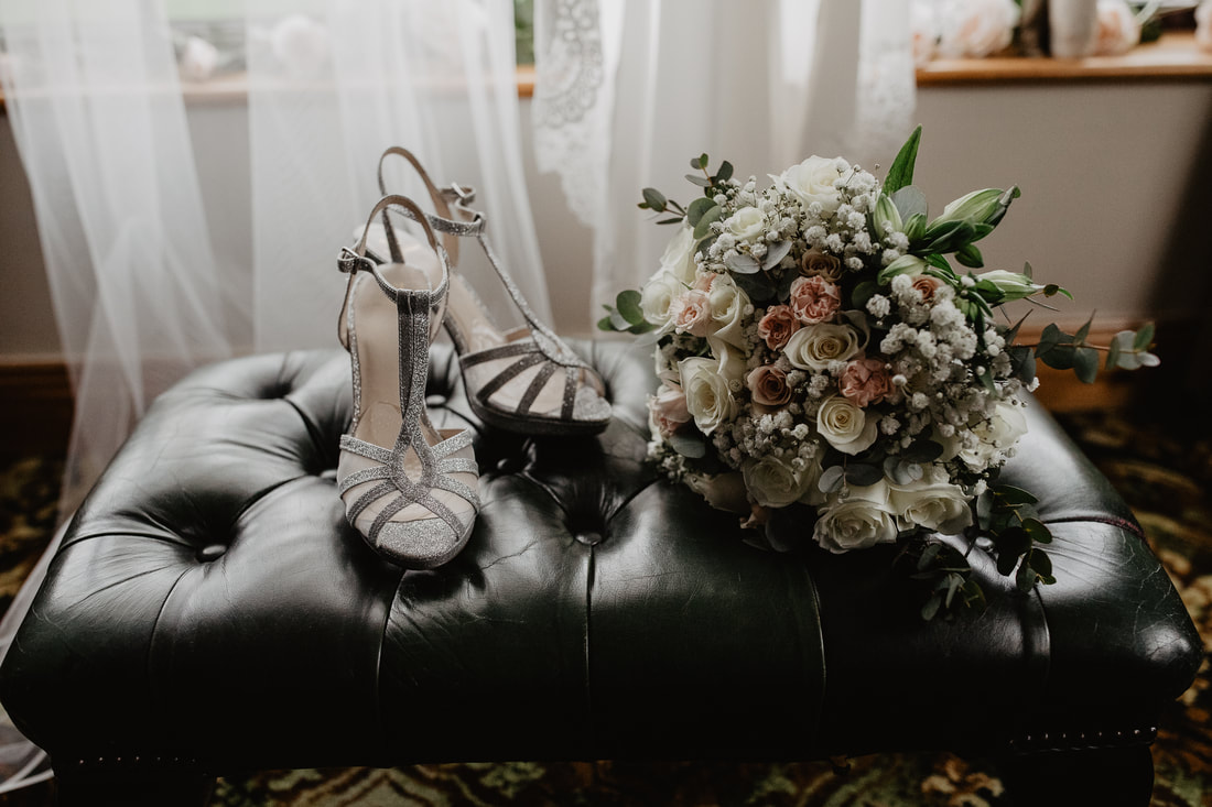 Wedding shoes and bouquet on a leather stool. Photographer Mario Vaitkus 