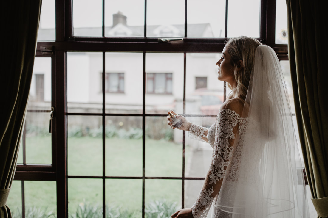Perfume spray. Bride standing at a window, getting some perfume
