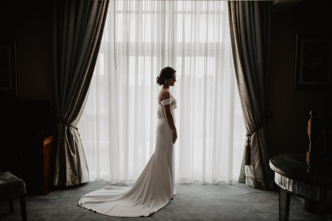 Bride in a wedding dress at a window at Knightsbrook hotel. Photo by Mario Vaitkus